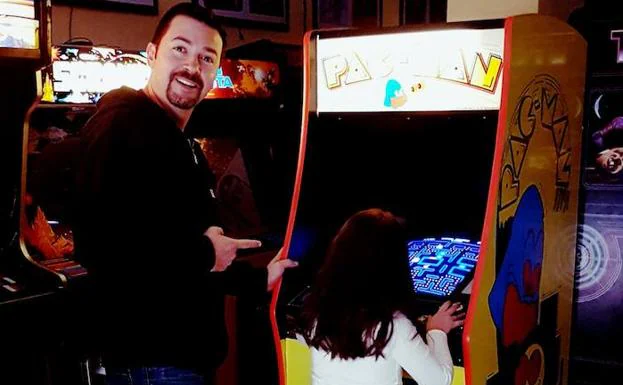 José María Litarte señala a su hija mientras juega al ‘Pac Man’ o ‘comecocos’.