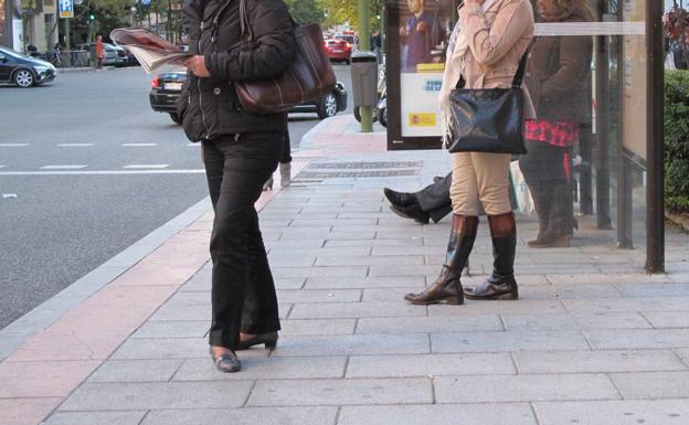 Dos mujeres esperan en una parada de autobús.