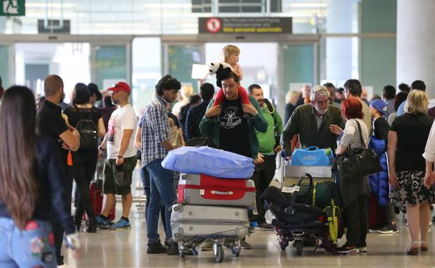 Pasajeros transitan por la terminal del aeropuerto de Málaga en busca de sus mostradores para facturar las maletas. 