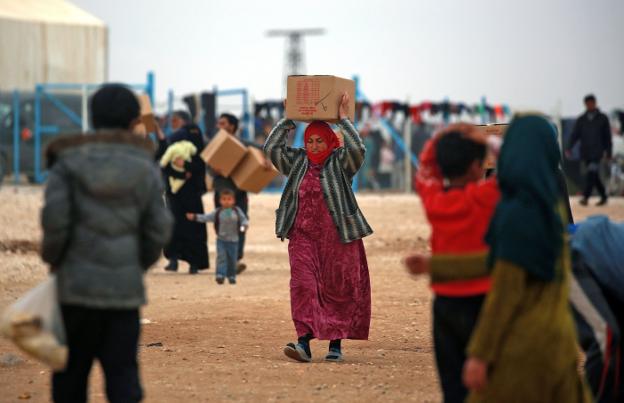 Una mujer siria transporta una caja con ayuda humanitaria en el campamento de refugiados de la localidad de Deir Ezzor. :: D. souleiman / afp