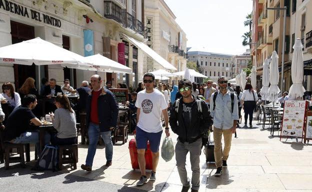 Turistas avanzan con sus maletas por la calle Alcazabilla en busca de la vivienda en la que se alojan.