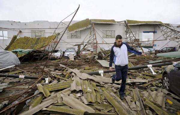 Un joven camina sobre los restos del tejado de un parking que se derrumbó, en el barrio malagueño de San Andrés. 