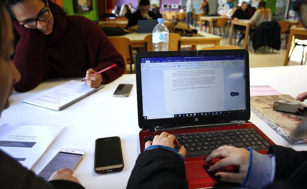 Estudiantes, con sus móviles y portátiles en las mesas de trabajo habilitadas en el vestíbulo de la Facultad de Económicas. 