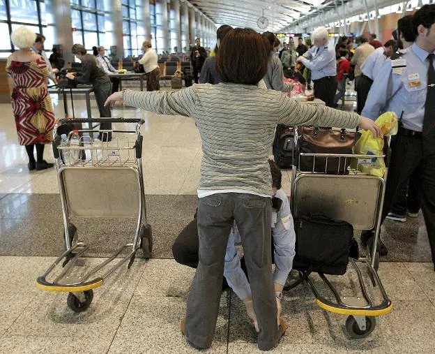 Un vigilante de seguridad registra a una pasajera en el aeropuerto de Madrid-Barajas. :: j. martín / efe