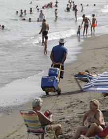Imagen secundaria 2 - Un turista se interesa por los colgantes. Un mantero vende sus productos en el paseo marítimo de Marbella. También venden comida y bebida en la playa.