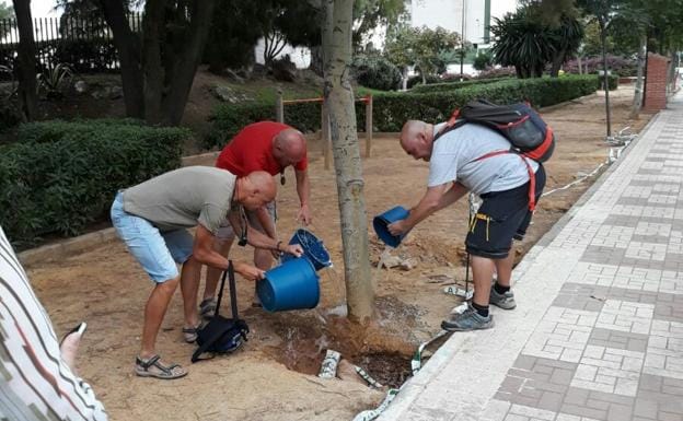 Vecinos echan agua a los árboles en los jardines Alberto Suárez 'Pipi' ante la falta de riego.