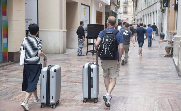 Turistas se dirigen hacia su alojamiento, en el centro histórico de Málaga.