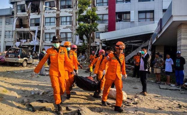 Personal de rescate portan el cuerpo de una víctima tras el terremoto y posterior tsunami en Palu. 
