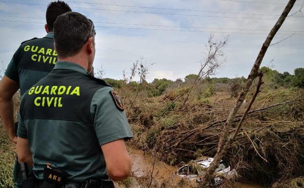 Una pareja de guardias civiles observa un coche hundido.