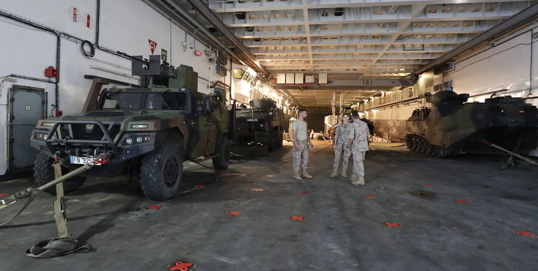 Personal de infantería de Marina delante del dique inundable para el desembarco de unidades anfibias y junto a los vehículos pesados que se guardan en este hangar..