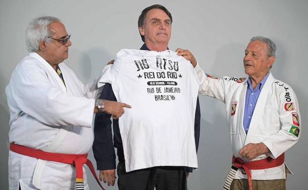 Bolsonaro recibe una camiseta de manos de los fundadores de la primera escuela de jiu-jitsu de Brasil.
