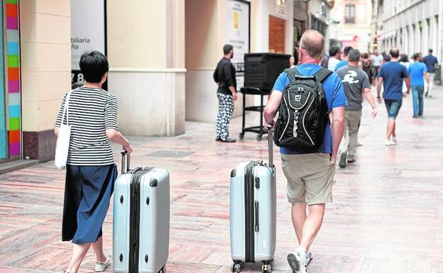 Turistas se dirigen hacia su alojamiento en el Centro Histórico de Málaga. 