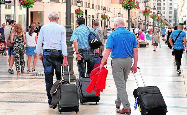 Turistas con maletas, en el Centro de Málaga en busca de su alojamiento.