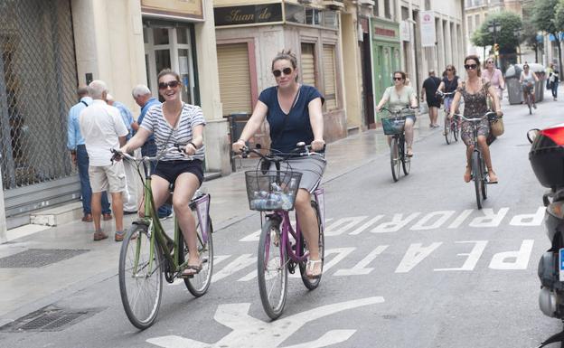 Turistas conocen la ciudad desplazándose en bicicleta.