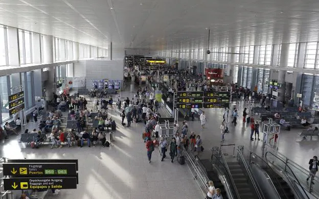 Pasajeros esperan en las puertas de embarque del aeropuerto de Málaga la subida a sus respectivos aviones. 