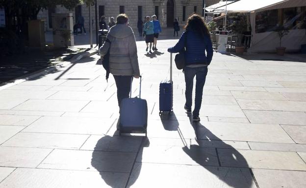 Turistas avanzan por el Centro de Málaga hacia su alojamiento.