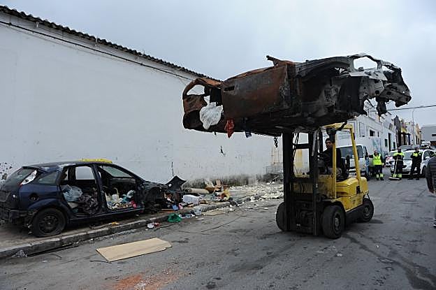 Un torito transporta uno de los vehículos abandonados en el polígono La Ermita hasta la plataforma de la grúa. 