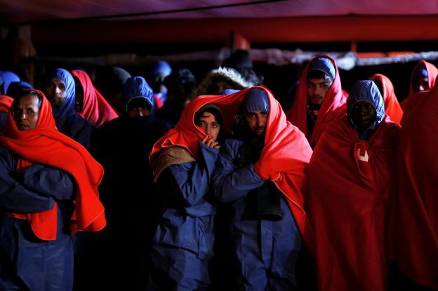 Un grupo de migrantes rescatados en el mar se tapa con mantas tras llegar al puerto de Málaga el pasado jueves. :: Jon Nazca / reuters