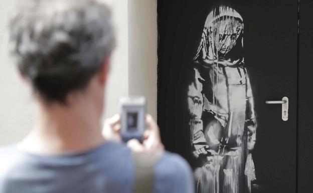 Un hombre hace una foto a la obra atribuida a Banksy en la sala Bataclan. 