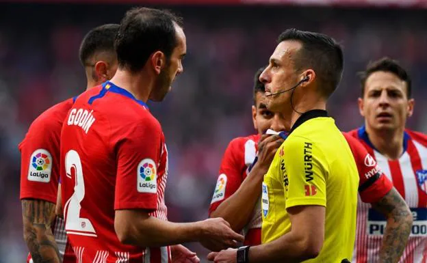 Los jugadores del Atlético hablan con Estrada Fernández tras la acción del penalti a Vinicius.