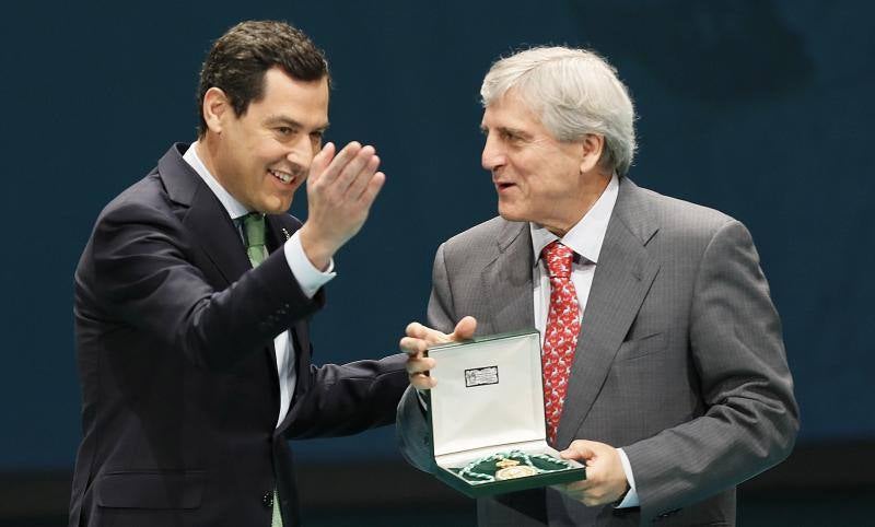 El presidente andaluz, Juanma Moreno (i), entrega al representante del Instituto de Biomedicina de Sevilla la Medalla de Andalucía durante el acto de entrega con motivo del día de la comunidad autónoma