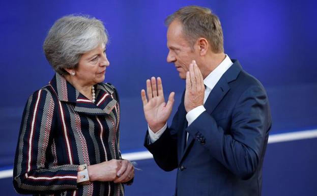 El presidente del Consejo Europeo, Donald Tusk, conversa con la primera ministra británica, Theresa May.