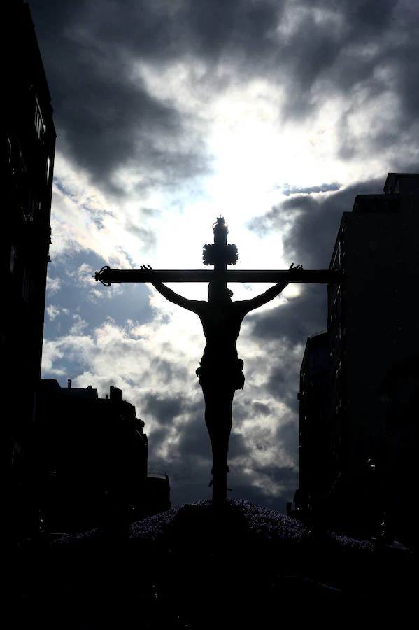 La silueta del Cristo de los Milagros, de la Cofradía de Zamarrilla, recortada en un cielo de nubes, a su paso por la calle Mármoles. 