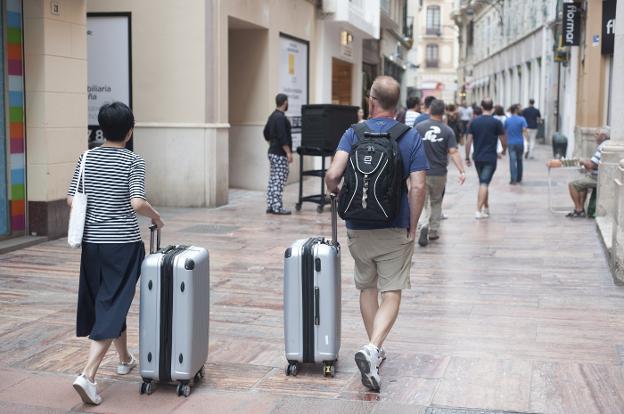 Turistas se desplazan por el Centro Histórico de Málaga en busca de su alojamiento. :: sur