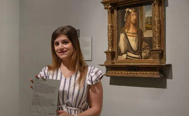 Patricia Chica posa con su cartela junto al 'Autorretrato' de Durero del Museo del Prado. 