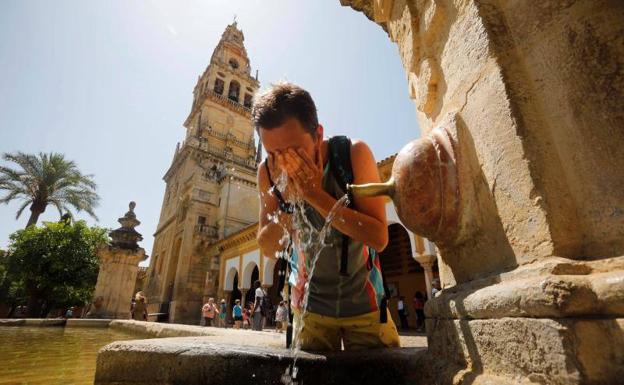 Un turista se refresca en una de las fuentes del patio de los Naranjos de la Mezquita-Catedral de Córdoba.