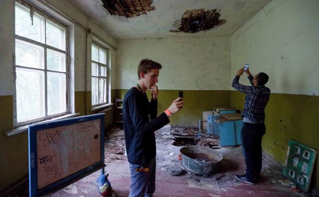 Turistas fotografían el interior de una guardería abandonada en el pueblo de Kopachi, cerca de la central.