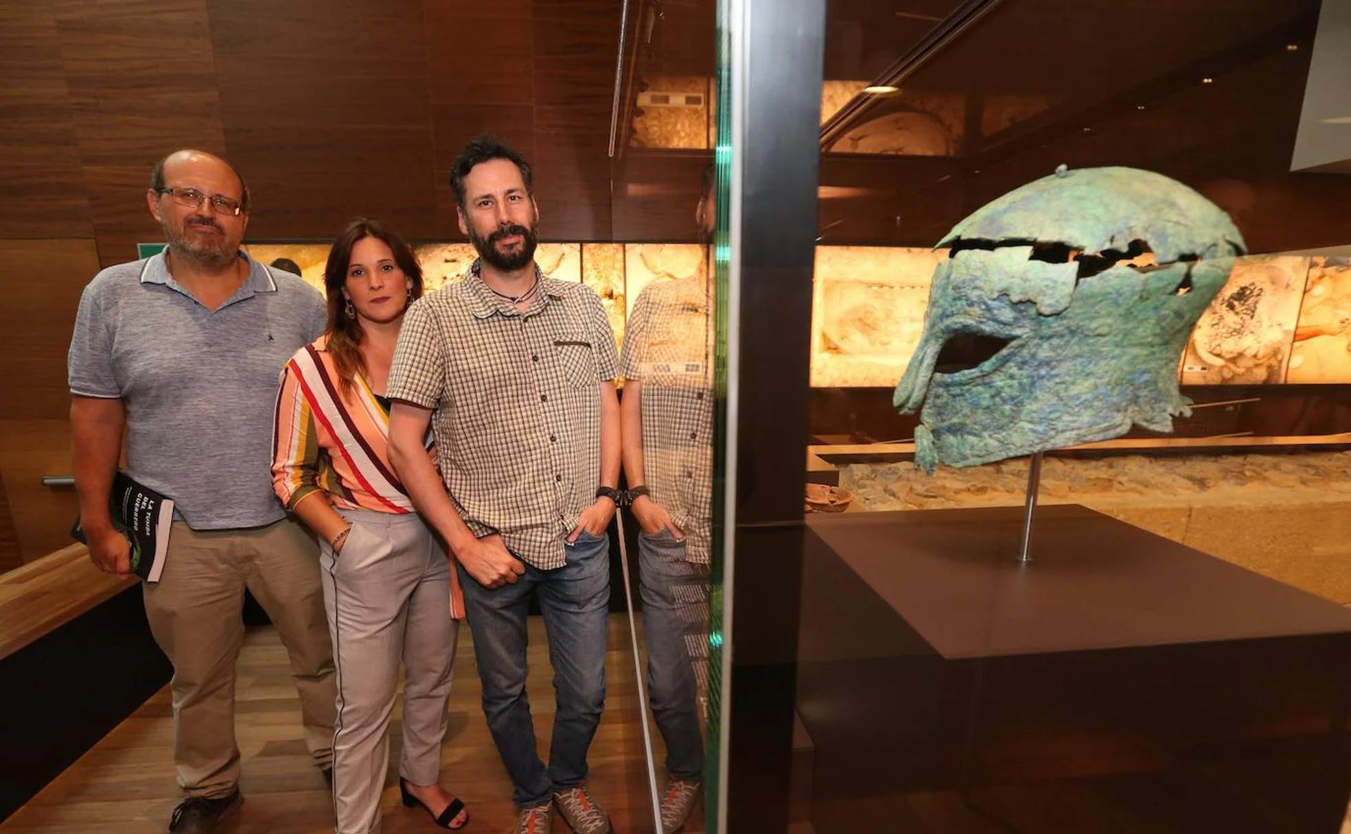 Los arqueólogos Eduardo García Alfonso (izq.), Sonia López y David García, junto al casco corintio encontrado en la tumba del guerrero y exhibido en el Museo de Málaga.