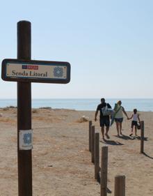 Imagen secundaria 2 - Arriba, hay varios carteles que señalan que estas playas forman una reserva ecológica. Abajo, a la izquierda, puente de madera por donde discurre uno de los tramos de la Senda Litoral. A la derecha, cartel indicativo de la Senda Litoral de Málaga