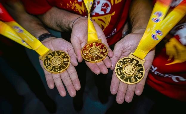 Imagen principal - Los malagueños muestran sus medallas y posan con la copa de campeones del mundo. 