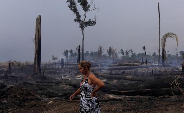 Una mujer pasa junto a una zona de la Amazonia brasileña quemada por agricultores para ampliar sus cultivos. 