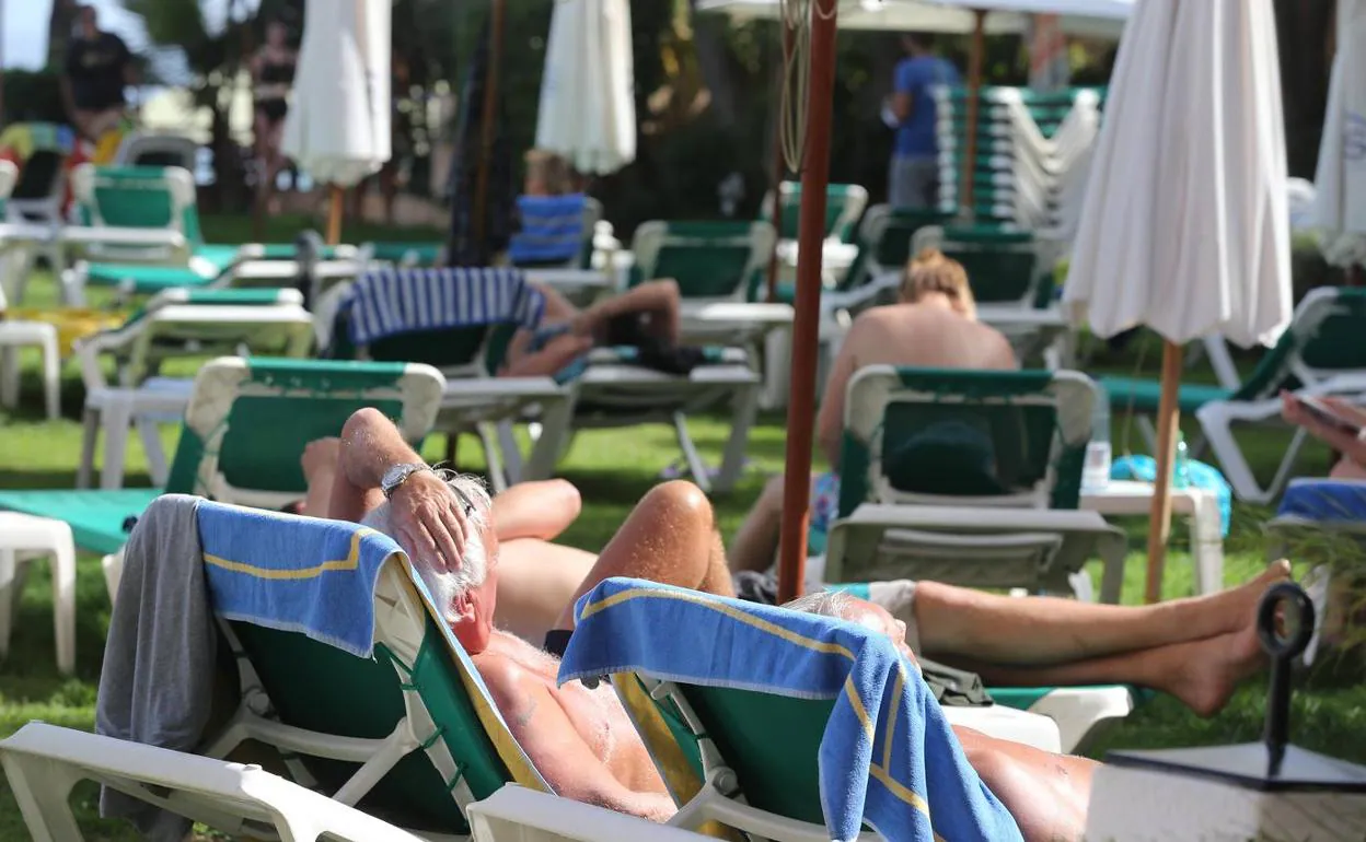 Turistas toman el sol en la piscina de un hotel de Torremolinos. 