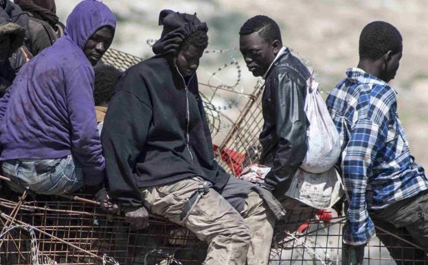 Un inmigrante encaramado en una valla fronteriza muestra sus pies ensangrentados. 