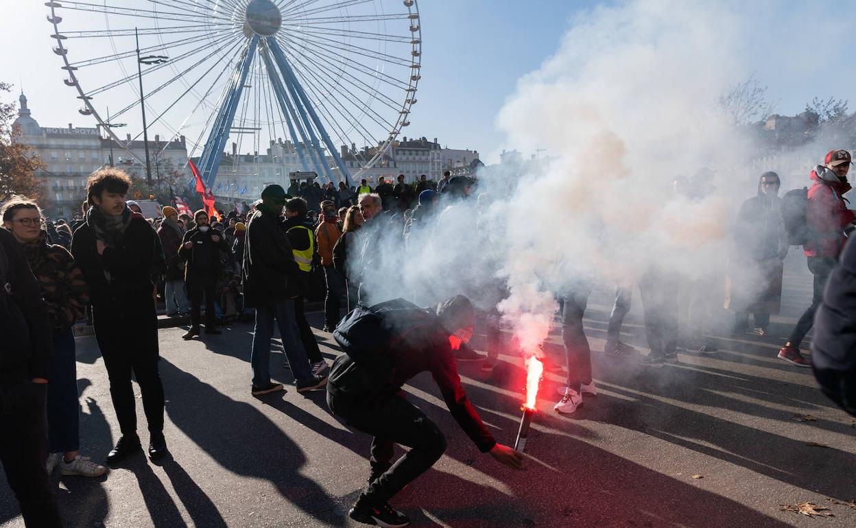 Un manifestante enciende una bengala en una protesta en Lyon.