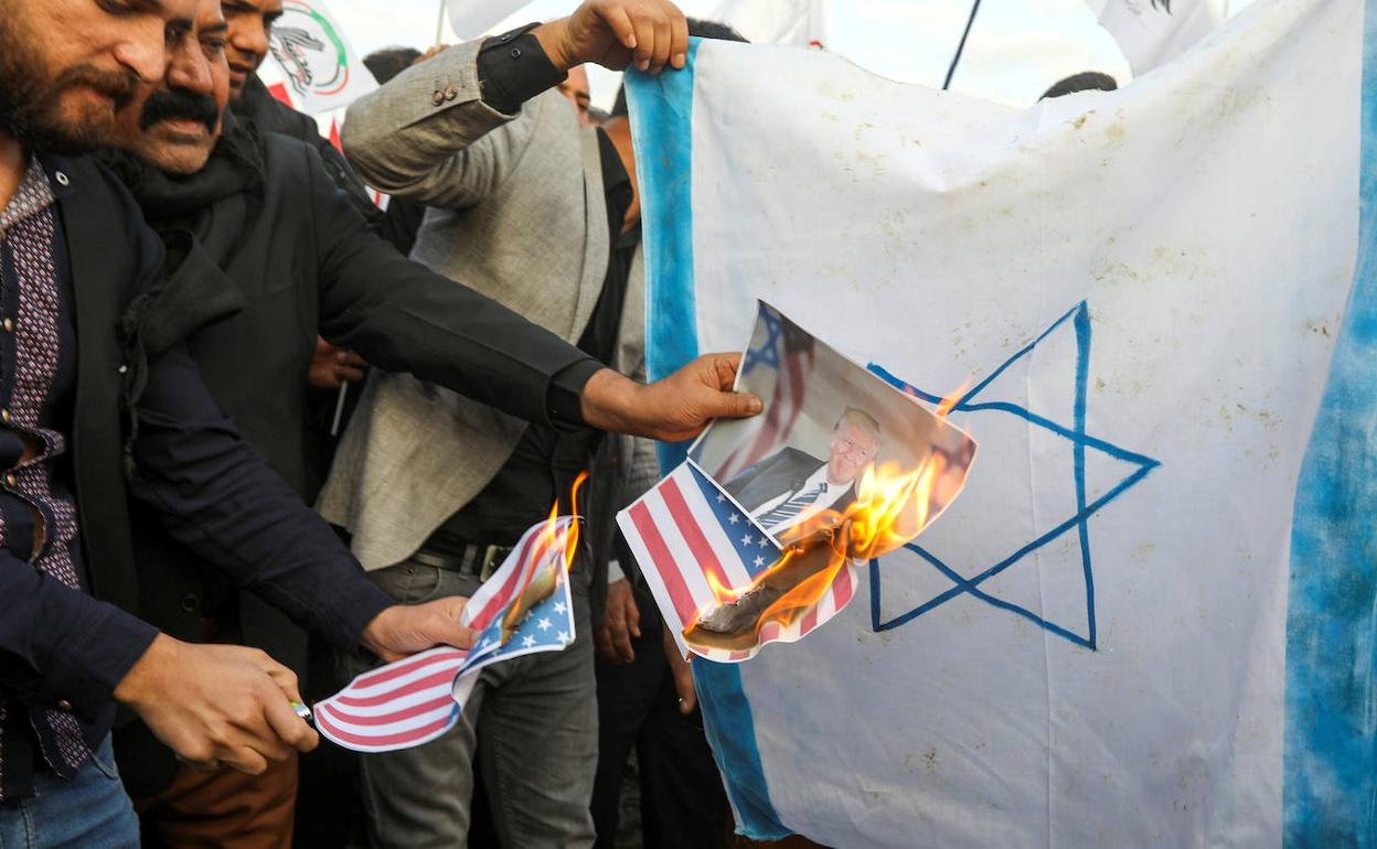 Ciudadanos iraquíes prenden fuego a una bandera de EE UU y a una foto de Trump.