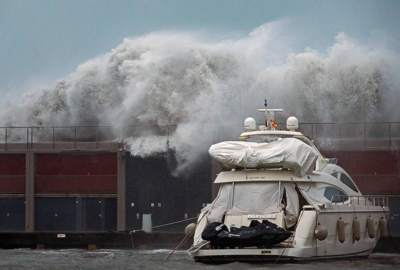 Grandes olas sobrepasan el espigón del Puerto Olímpico de Barcelona hundiendo uno de los barcos atracados