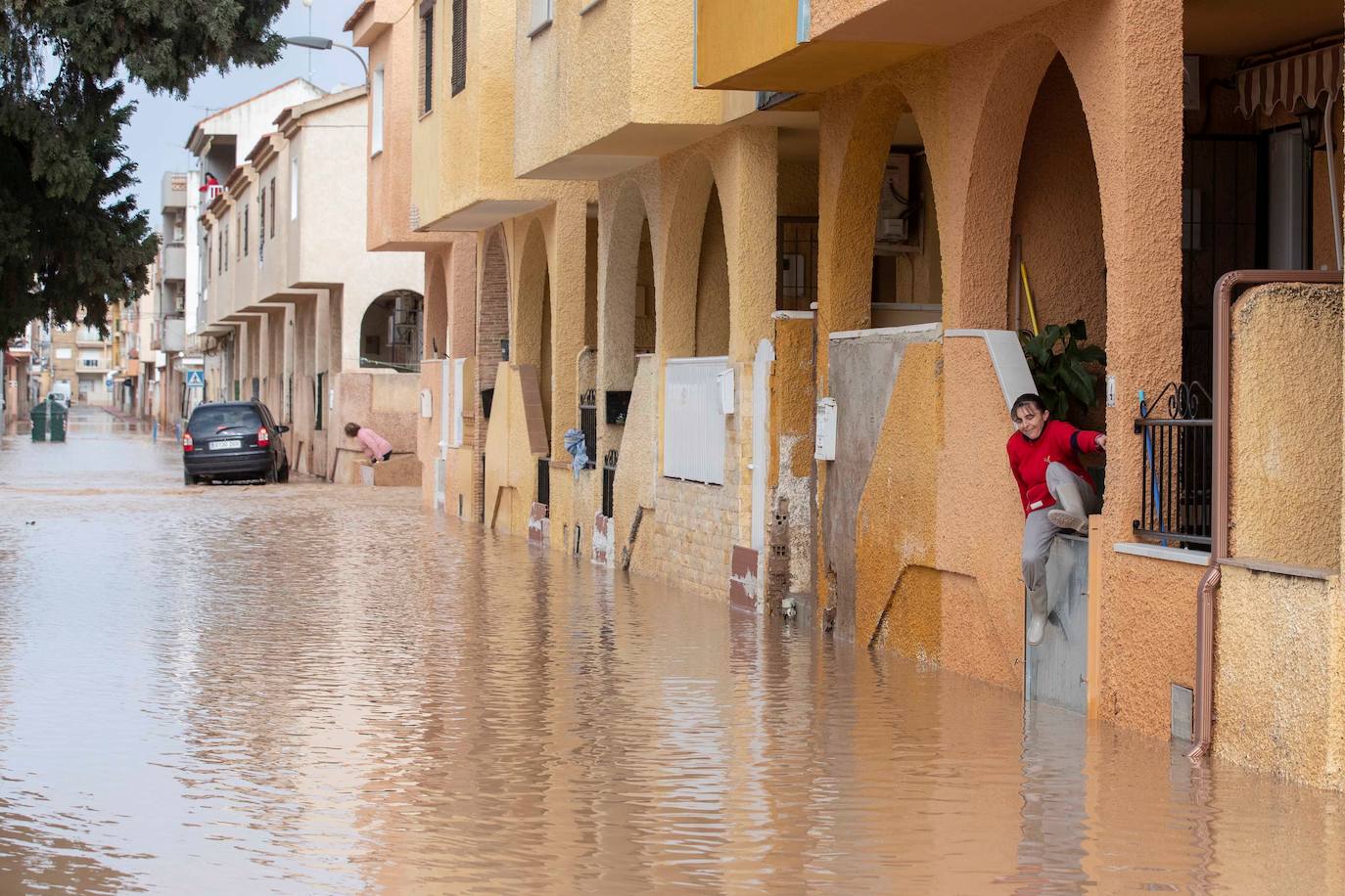 Una mujer intenta salir de su casa a la calle inundada en el municipio de Los Alcázares, (Murcia)