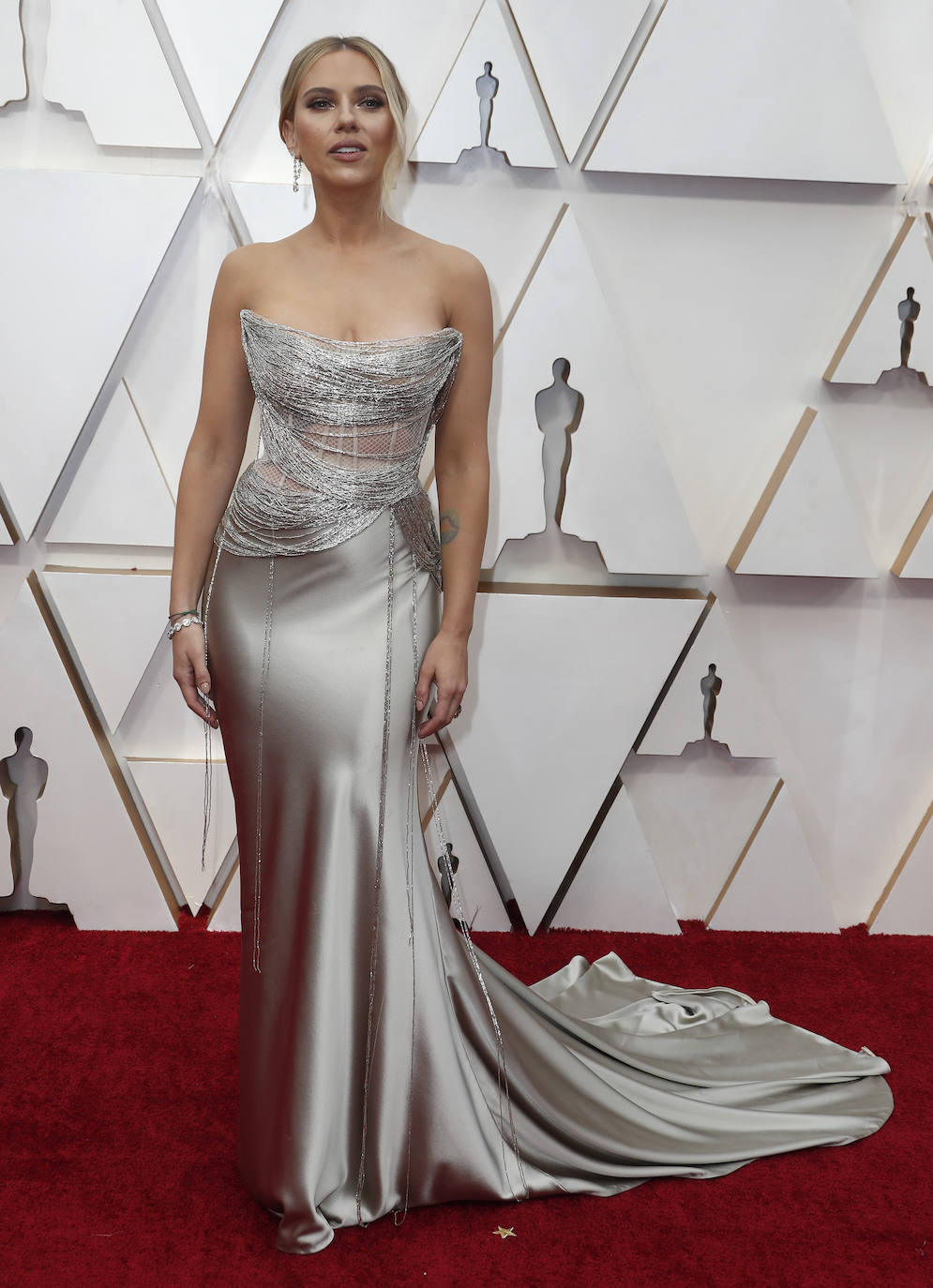 Una vez más, Scarlett Johansson demuestra que sabe sacar partido a sus curvas con un look sexy muy femenino que no dejó indiferentes. Para la alfombra de los Oscar eligió un original vestido de seda plateado de Oscar de la Renta con estudiadas transparencias, escote palabra de honor y chorreras de cristales.