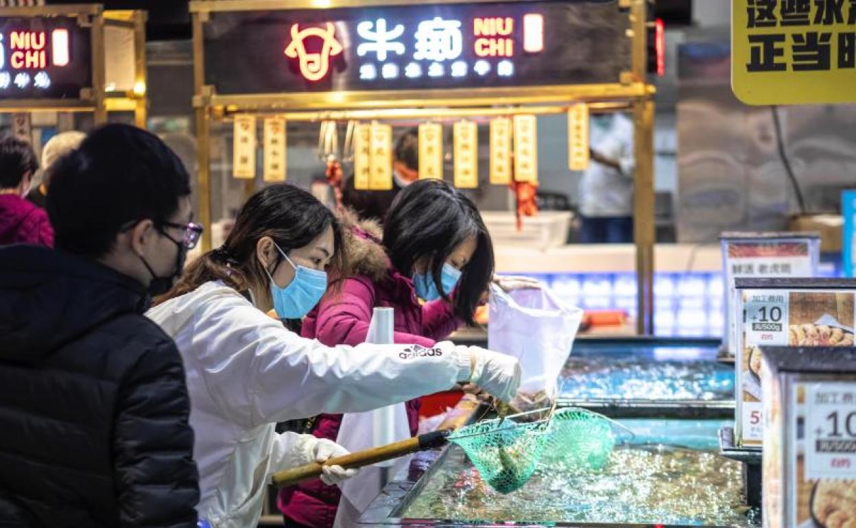 Personas con máscaras protectoras en un supermercado de Guangzhou 