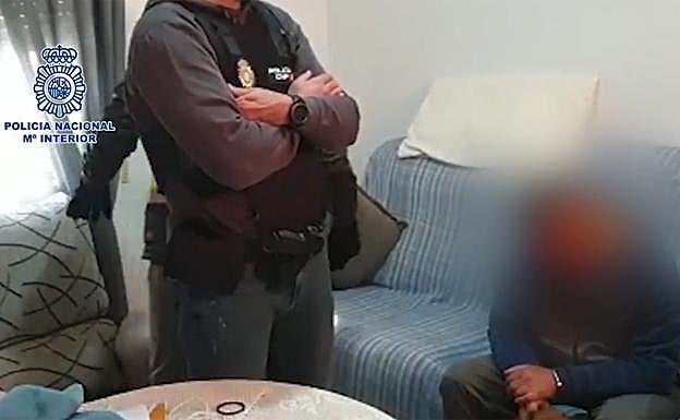 Policías en un registro domiciliario junto a uno de los detenidos.