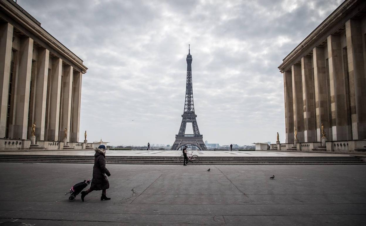 Una mujer ataviada con una mascarilla atraviesa la plaza de Trocadero en París