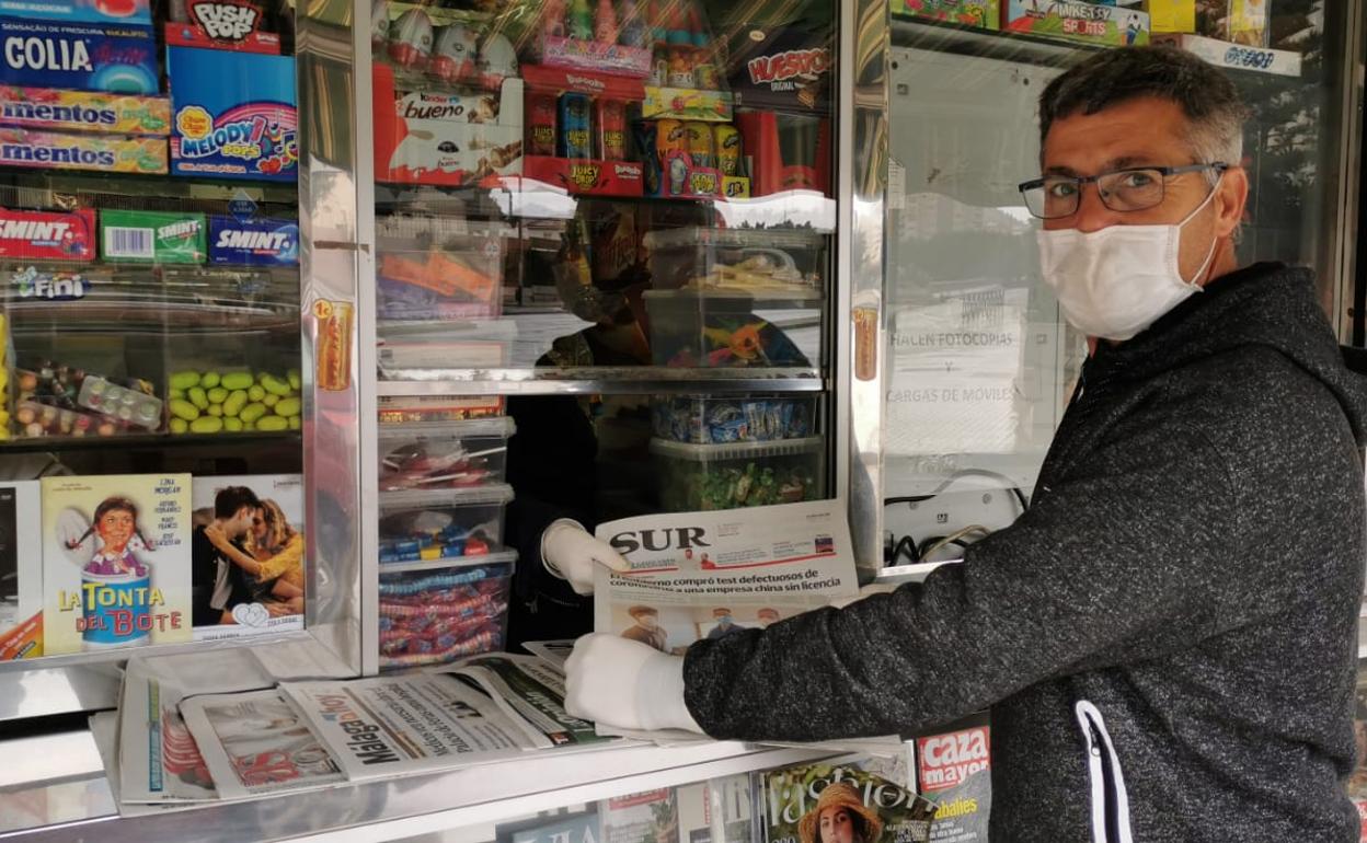 Un lector con un ejemplar de SUR en un quiosco de Málaga. 