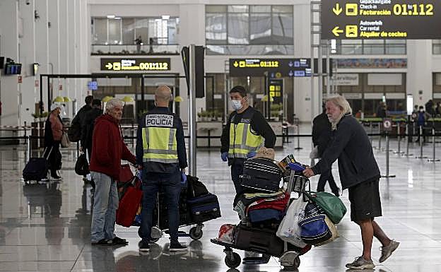 Agentes de la Policía Nacional, junto a dos personas sin hogar en el aeropuerto. 