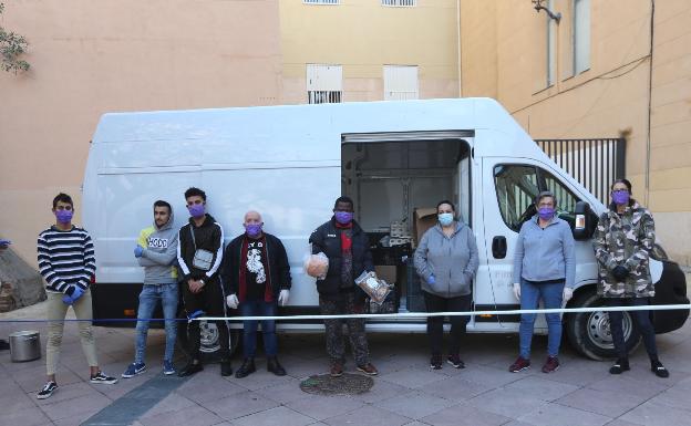 Los voluntarios, ayer delante de la furgoneta y el cordón de seguridad que montaron para repartir.