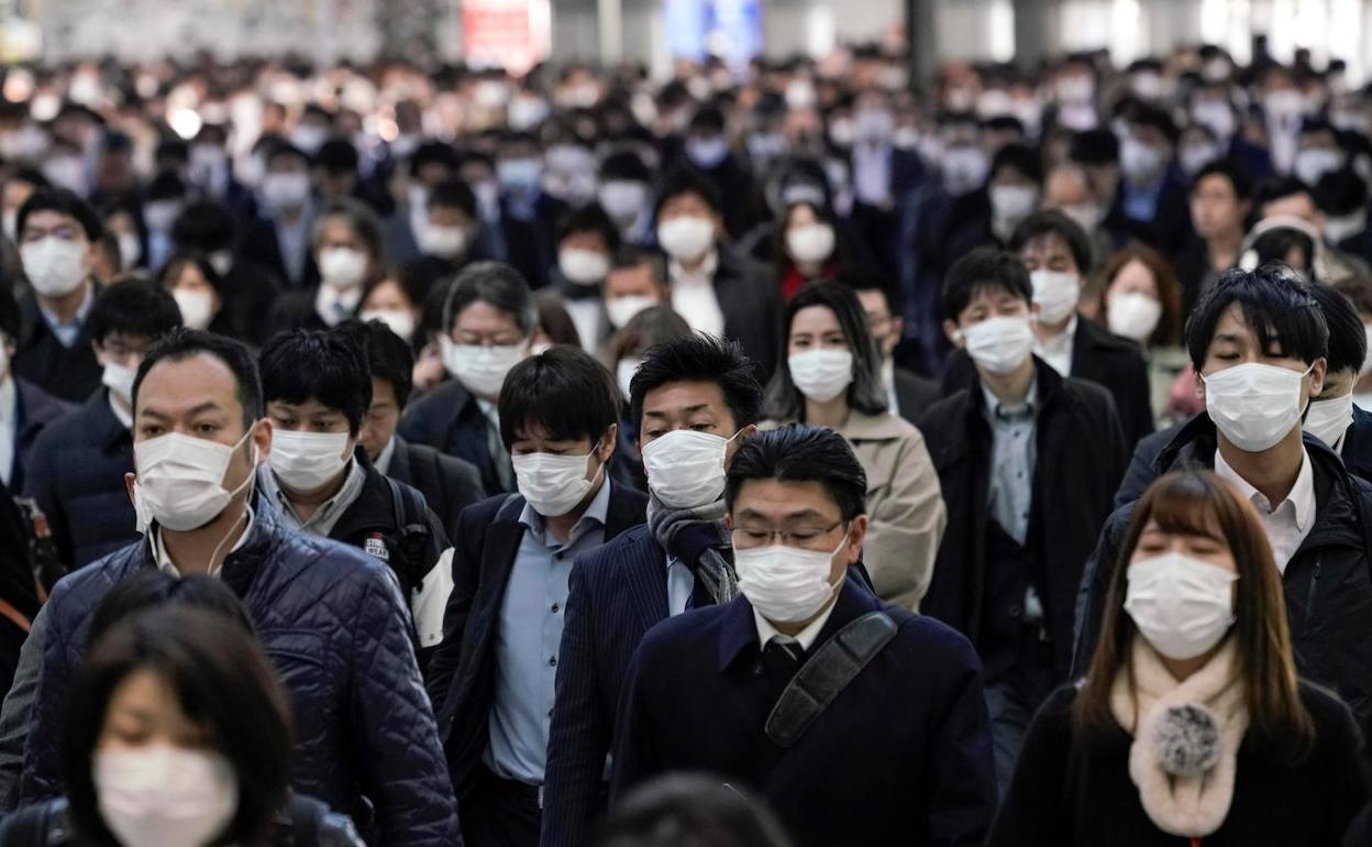 Trabajadores protegidos con mascarillas acuden a sus oficinas en Tokio. 