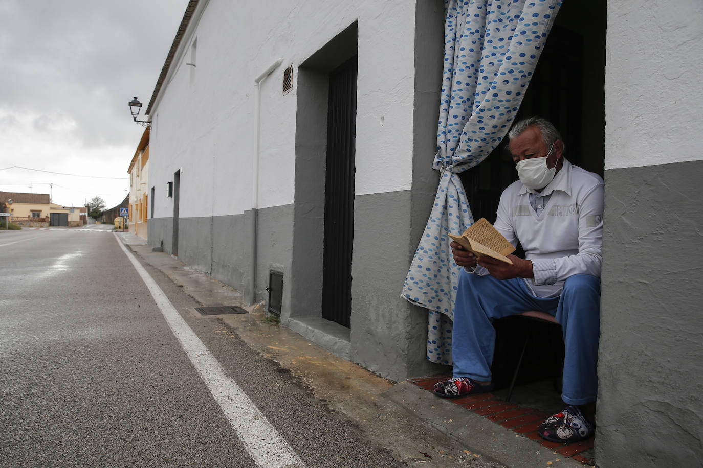 Un vecino lee en la puerta de su casa en Peñón de Zapata